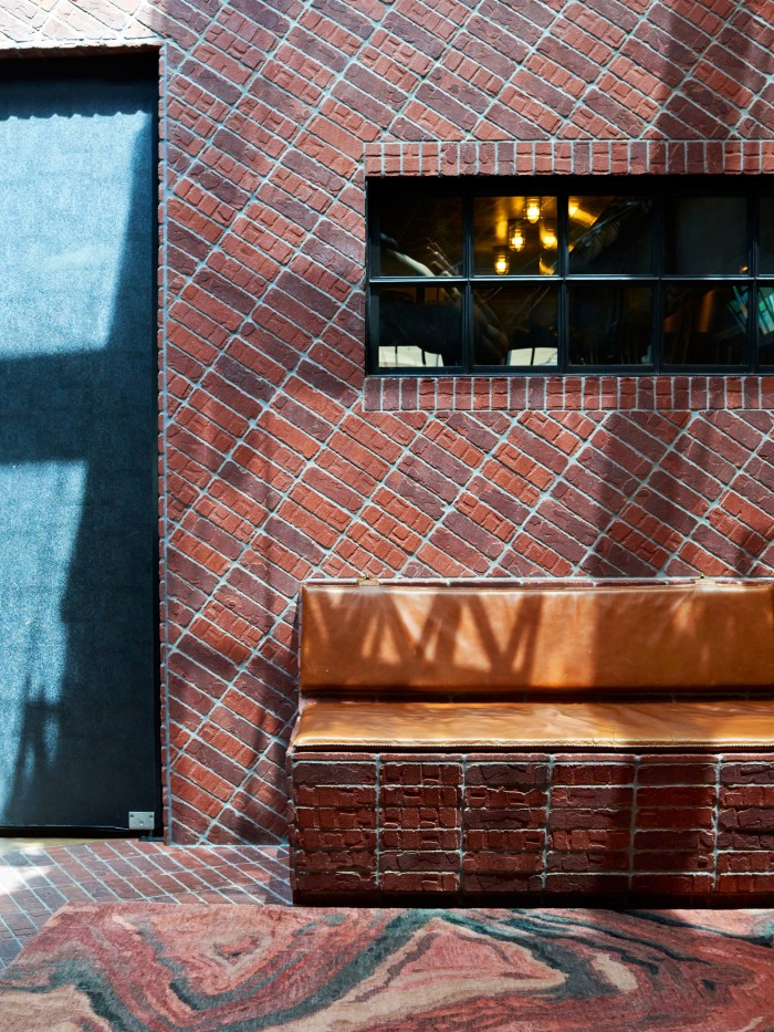 Laguna rug in a lobby with brick walls and orange bench 