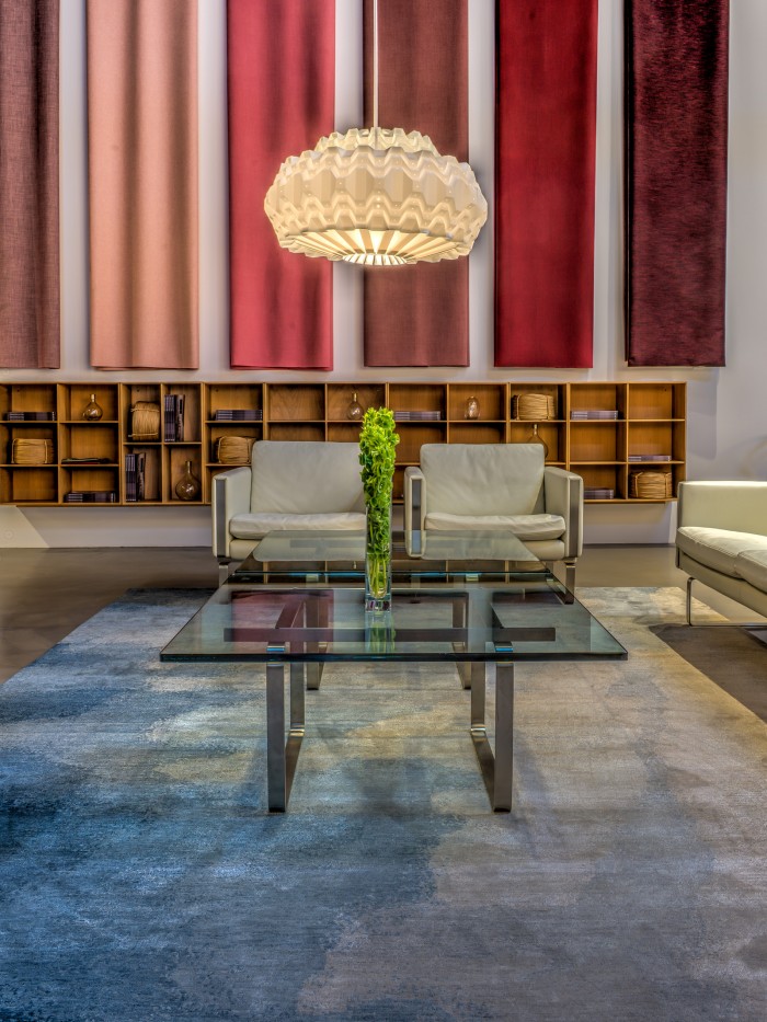 Nimbus rug displayed in hotel lobby with red curtains and white chairs